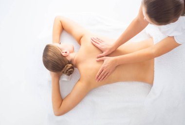 Beyaz arka planda masaj yaptıran genç bir kadın. Spa, sağlık ve dinlenme konsepti.