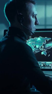 Soluk bir askeri kontrol odasında, çok önemli operasyonel dron verilerini gösteren birden fazla bilgisayar ekranına odaklanmış bir asker. Modern savaş kavramı.