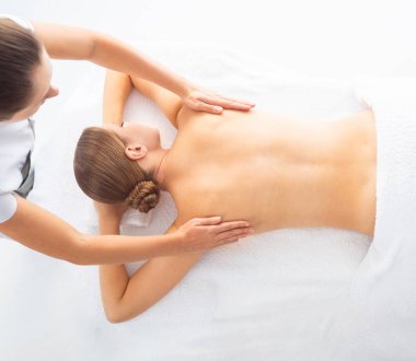 Beyaz arka planda masaj yaptıran genç bir kadın. Spa, sağlık ve dinlenme konsepti.