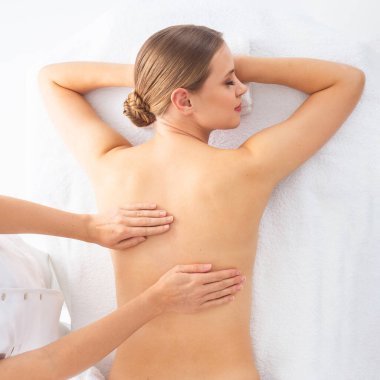 Beyaz arka planda masaj yaptıran genç bir kadın. Spa, sağlık ve dinlenme konsepti.