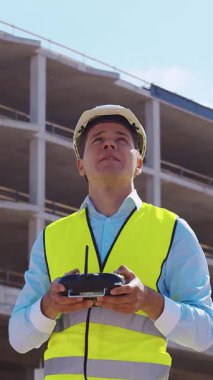 İnşaat alanının önünde duran profesyonel müteahhit. Kasklı ve yelekli ustabaşı. Ofis binası ve vinç arka planı. İş, gayrimenkul ve yatırım kavramları.