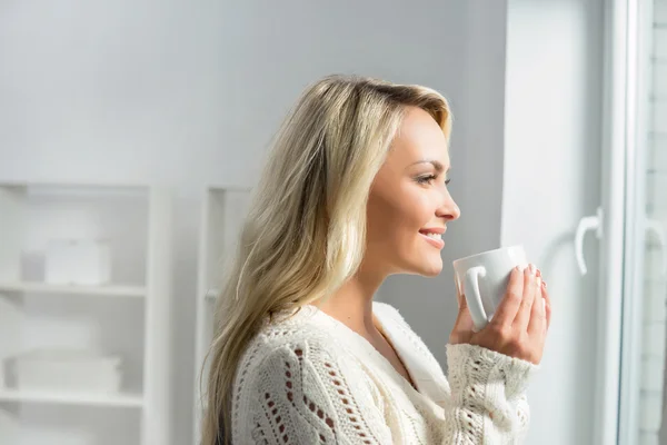 Donna che beve caffè e guarda attraverso la finestra — Foto Stock