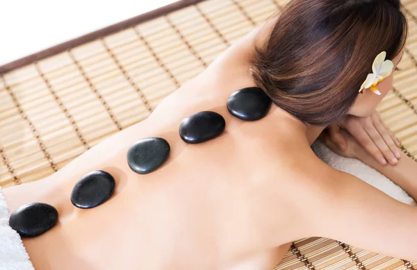 Mulher tendo pedras quentes em suas costas — Fotografia de Stock