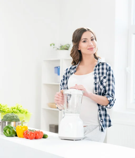 Pregnant woman cooking with a blender. — Stock Photo, Image