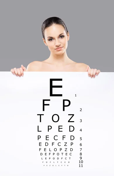 Attraktive Frau mit einem Banner des Test Vision Table vor grauem Hintergrund — Stockfoto