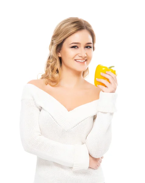 Young and beautiful woman in a white cardigan eating a yellow paprika — Stock Photo, Image