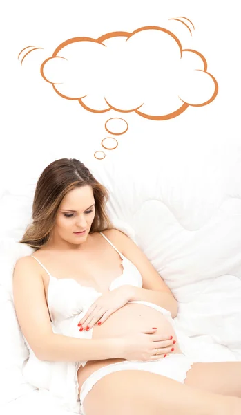 Krásná těhotná žena v posteli s konceptuální cloud — Stock fotografie