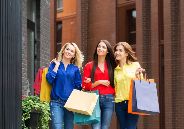 Drie jonge mooie vriendinnen wandelen met shopping tassen — Stockfoto