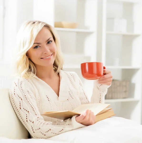 Красива усміхнена щаслива жінка читає книгу і має чашку кави Стокове Зображення