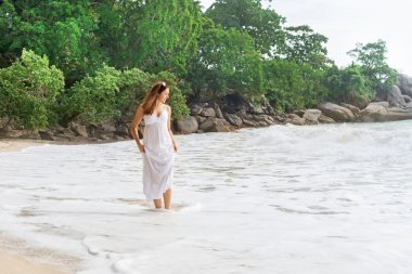 Sahilde yürüyüş ve giysi çekerek çekici, genç kadın