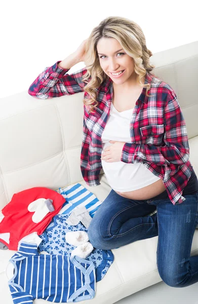 Красивая беременная блондинка с детской одеждой — стоковое фото