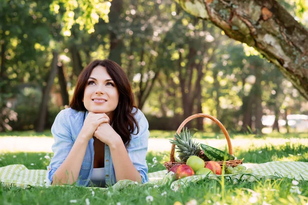 Vrouw liggend op een mat met mandje met fruit — Stockfoto