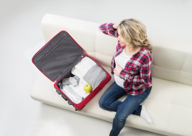 Young pregnant woman packing on a sofa clipart