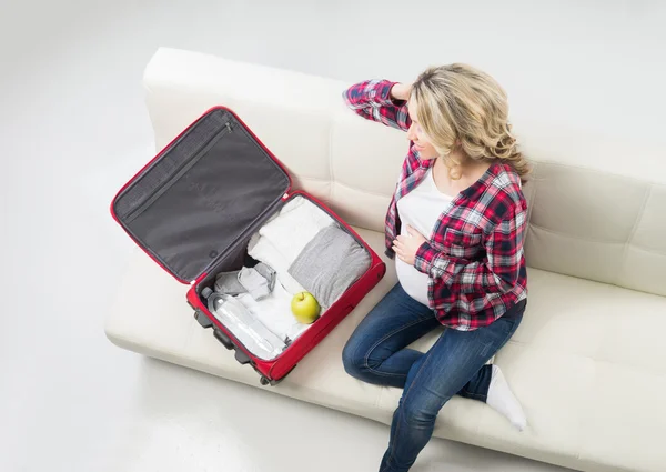 Young pregnant woman packing on a sofa — Stock Photo, Image