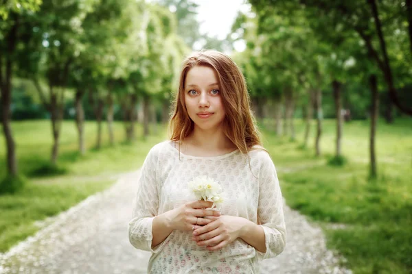 Jovem mulher segurando flores ao ar livre — Fotografia de Stock