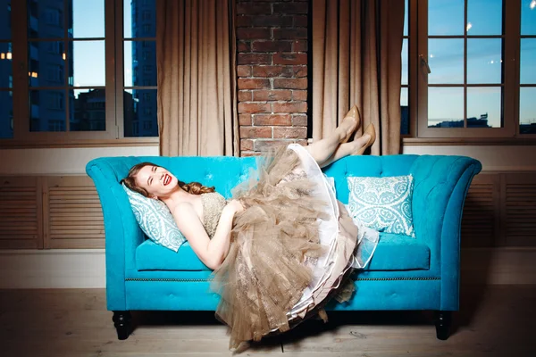Mujer de lujo acostada en un sofá azul — Foto de Stock