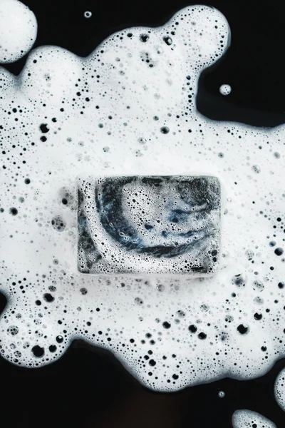 Угольное мыло в пене на черном — стоковое фото