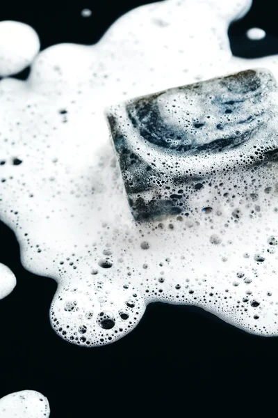 Dark soap in foam on black — Stock Photo, Image