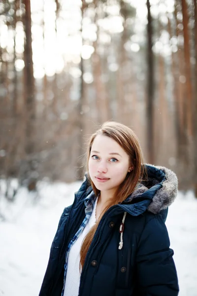 Стильная молодая женщина в зимней одежде стоит в зимнем лесу — стоковое фото