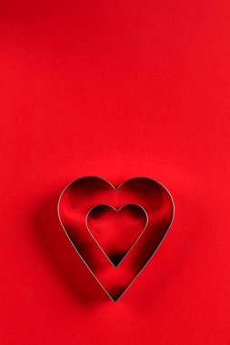 Sevgililer Günü minimalist tebrik kartı, kırmızı arka planda kalp şeklinde kurabiye kesiciler, güzel gölgeler, düz uzanmış