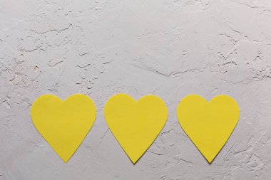 Sevgililer Günü minimalist tebrik kartı Pantone 2021 gri ve sarı renkler, desenli arka planda üç kağıt kalp, düz uzanmış