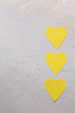 Sevgililer Günü minimalist tebrik kartı 2021 yılının en gri ve en parlak sarı renkleri, desenli arka planda üç kağıt kalp, düz yatıyordu.