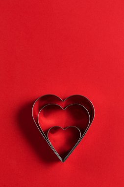 Sevgililer Günü minimalist tebrik kartı, kırmızı arka planda kalp şeklinde kurabiye kesiciler, güzel gölgeler, düz uzanmış