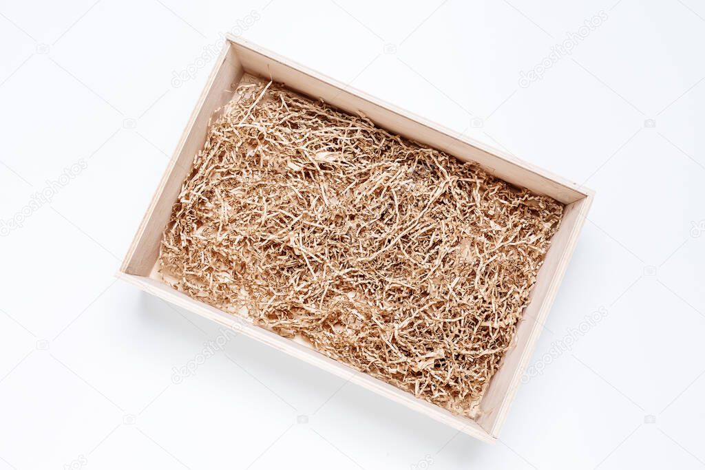 Opened gift wooden box with shredded paper filler on white background for product placement. Top view, mockup