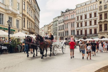 KRAKOW, POLAND - 21 Temmuz 2019: Polonya 'nın eski Krakow kasabasında at arabalarıyla süslenmiş atlar, Avrupa' nın turistik merkezi ve tatil beldesi
