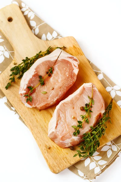 Fresh raw pork steaks on cutting board — Stock Photo, Image