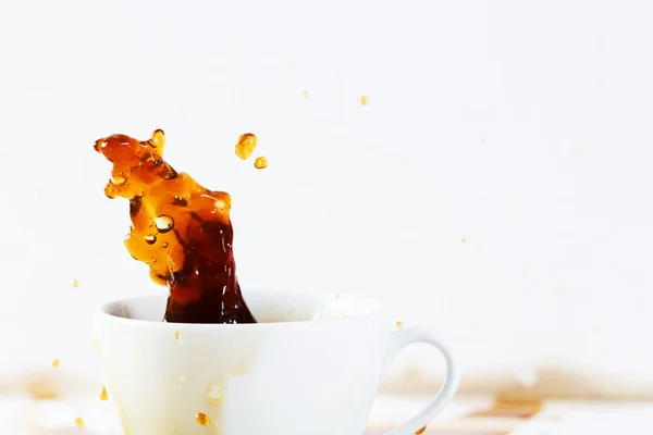 Cup of spilling coffee creating beautiful splash — Stock Photo, Image