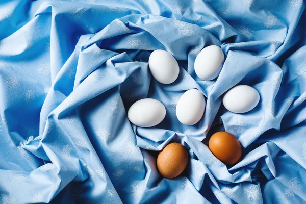 Pasen eieren op blauwe textiel gedrapeerd achtergrond — Stockfoto
