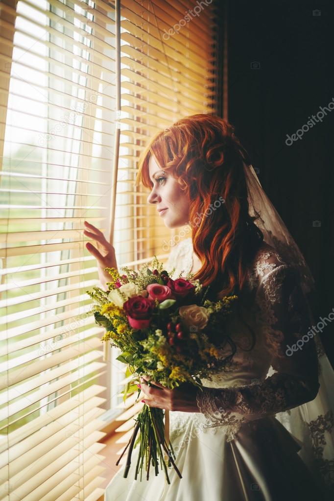 Beautiful red hair bride near window