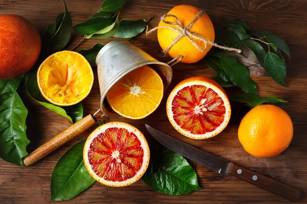 Stillleben mit orangefarbenen Früchten und grünen Blättern — Stockfoto