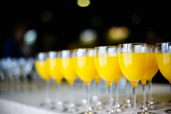 Række af briller med frisk appelsinjuice - Stock-foto