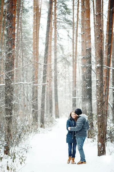 Pareja joven abrazándose en el bosque de invierno — Foto de Stock