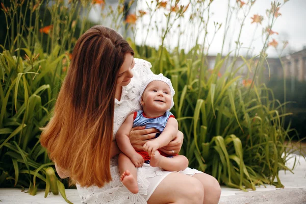 Şirin mutlu yürümeye başlayan çocuk annesinin diz sevgi dolu üzerinde oturan — Stok fotoğraf
