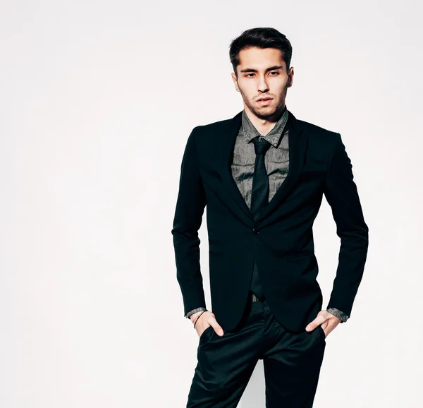 A young man in a fashionable suit posing. Indoor. Warm color. — Stock Photo, Image