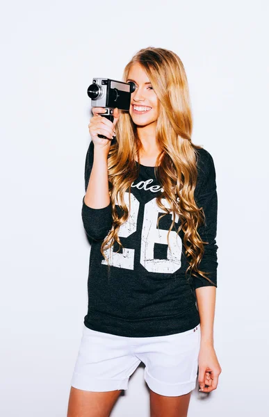 Vnitřní portrét krásná blondýna mladá žena drží ročník 8mm kameru. Teplé barvy. Stock Obrázky
