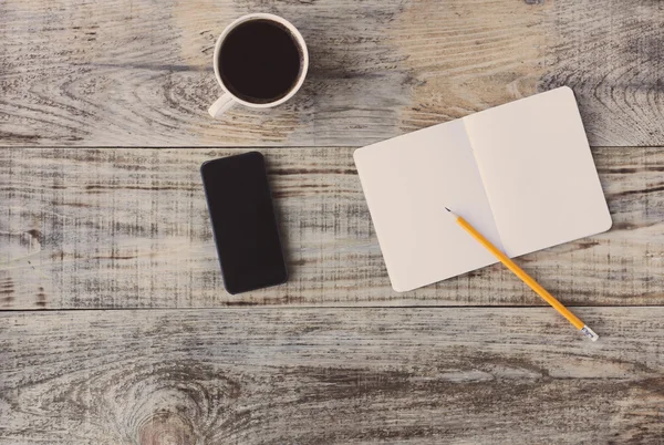 Draufsicht auf geöffnetes Notizbuch, Smartphone, Textmarker und andere Geräte auf hölzernem Bürotisch, alte Planken. Hipster-Stil — Stockfoto