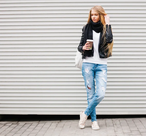 Retrato de una hermosa joven rubia con el pelo largo, posando en una calle con café y una mochila. Color al aire libre, caliente. Imágenes De Stock Sin Royalties Gratis