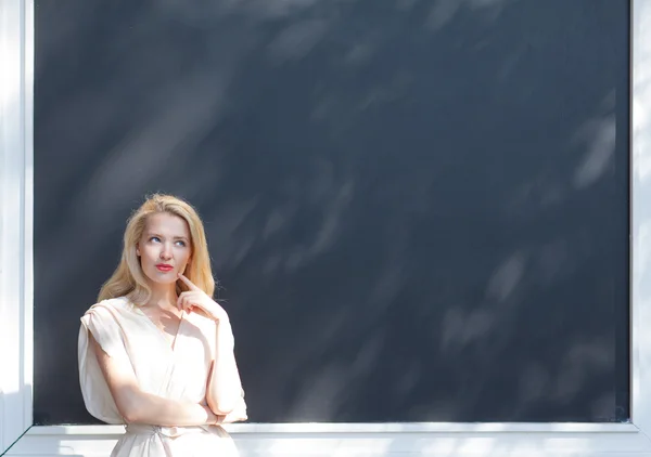 Retrato de al aire libre en un día caluroso de verano hermosa rubia sexy en una pose pensativa en el fondo de la pared con marco —  Fotos de Stock