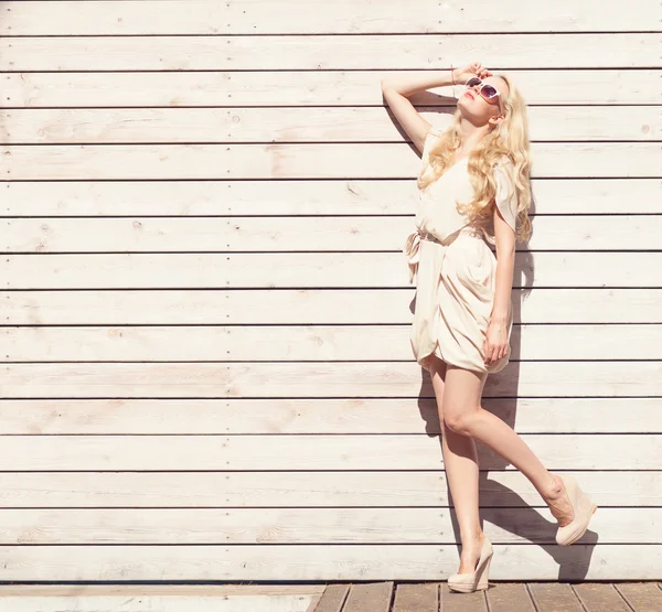 Відкритий літній чуттєвий портрет моди красива молода блондинка біла сукня, що стоїть на тлі дерев'яних дощок. Тоновані в теплих кольорах — стокове фото