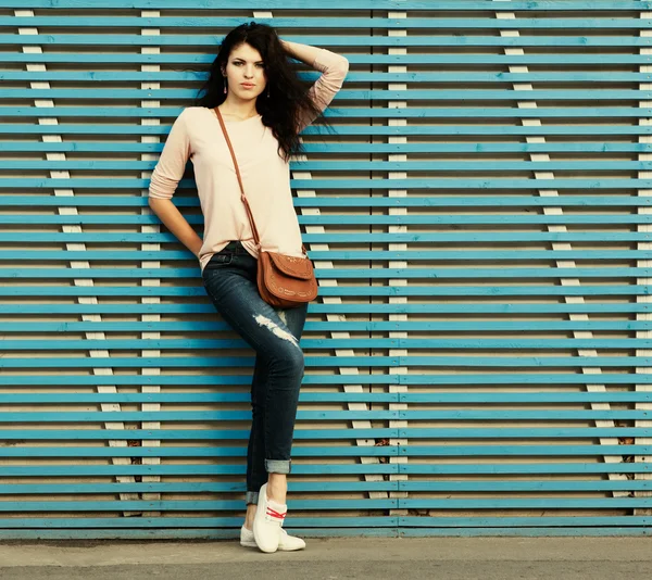 Schöne brünette Mädchen steht in der Nähe einer Wand aus farbigen Holzplanken — Stockfoto
