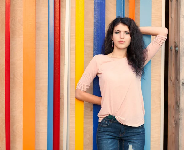 Hermosa chica alta con pelo largo morena de pie cerca de fondo de pared colorido —  Fotos de Stock
