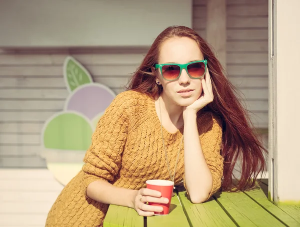Hermosa chica pelirroja en gafas de sol para la mesa de café al aire libre de verano —  Fotos de Stock