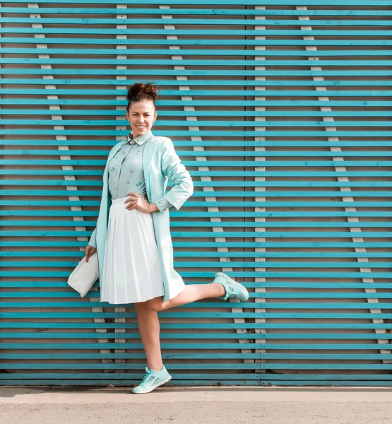 Linda morena hipster estilo menina fica perto de uma parede de tábuas de madeira coloridas — Fotografia de Stock