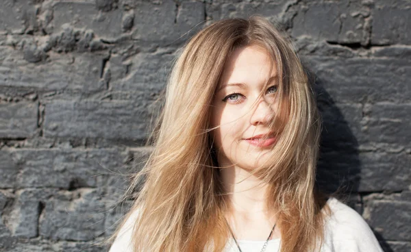 Ragazza in posa in un muro di mattoni neri. Il vento gli arruffò i capelli. Chiudete. All'aperto — Foto Stock