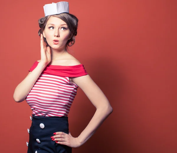 Beautiful pin-up girl dressed a sailor posing on red background — Stock Photo, Image