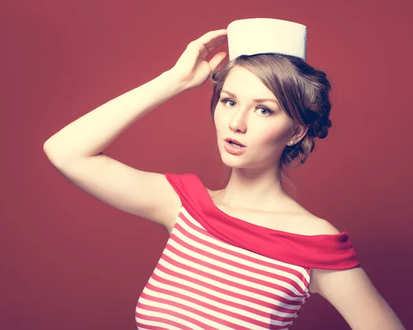 Mooi pin-up meisje gekleed een zeeman die zich voordeed op rode achtergrond — Stockfoto